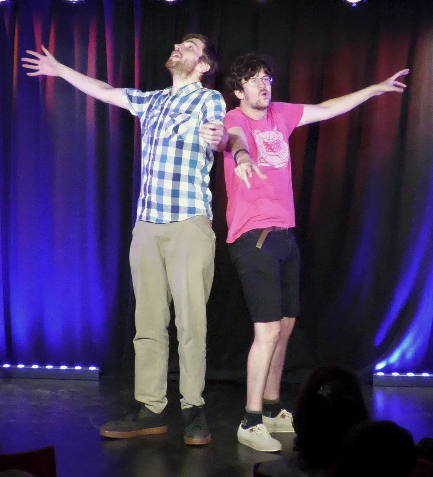 Deux improvisateurs jouent une scène, les bras largement ouverts.