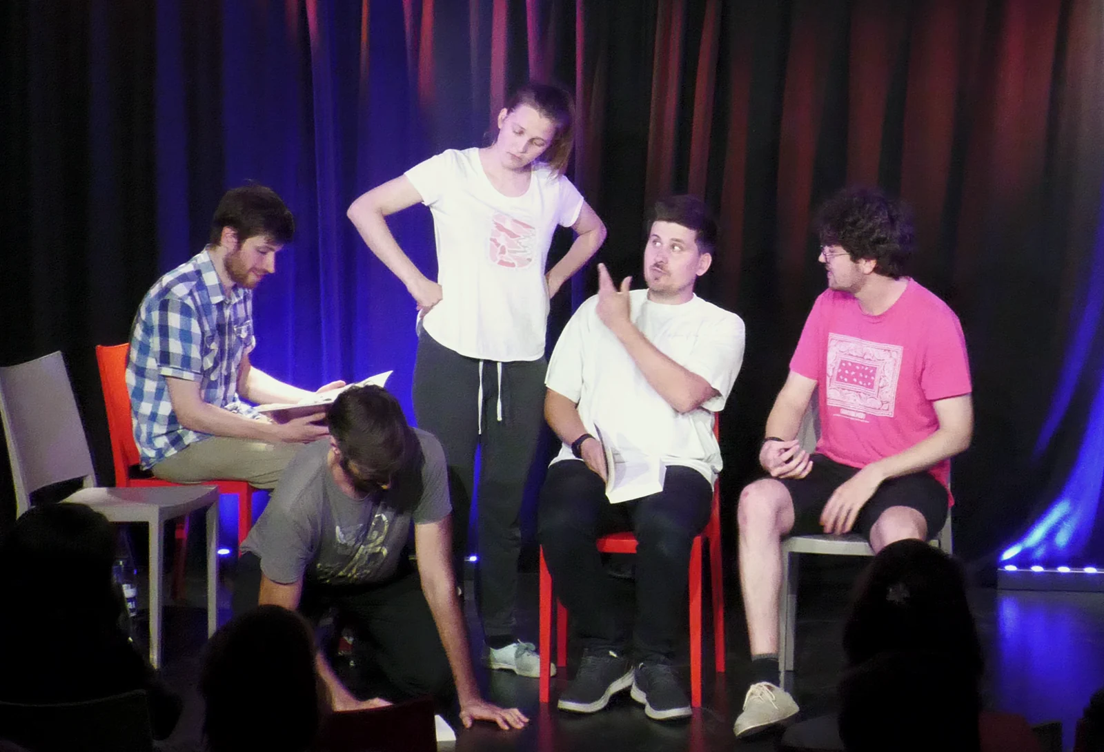 Cinq improvisateurs construisent une scène autour de plusieurs chaises.
